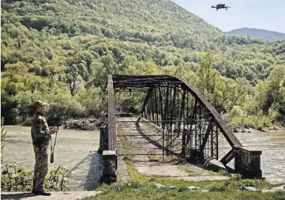  ?? NICOLE TUNG FOR THE NEW YORK TIMES ?? A Ukrainian border guard operating a drone over the Tysa River, where men have died trying to flee to Romania.