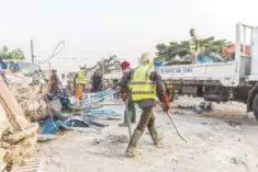  ??  ?? COTONOU: Workers demolish illegal structures as Benin security forces stand at a busy intersecti­on during an evacuation in downtown Cotonou on Jan 27, 2017. —AFP