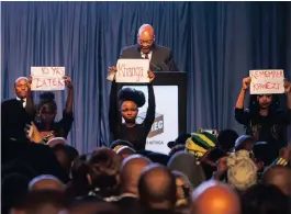  ??  ?? Silent female protesters hold up banners during President Jacob Zuma’s address at the South African local government election results ceremony.