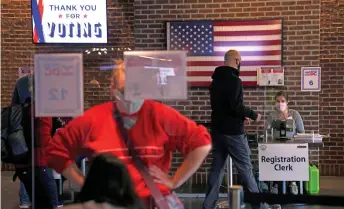  ?? — AFP photo ?? Poll workers help voters check in at an early voting center at Nationals Park in Washington, DC. With millions of workers still jobless and Covid-19 cases spiking, raising fears of renewed lockdowns in the US as there have been in Europe, Washington policymake­rs have failed to agree on a new rescue package to help households and businesses weather the crisis.