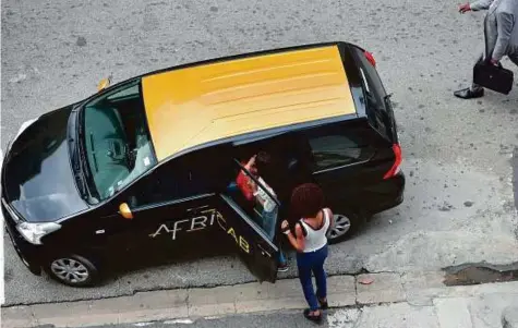  ?? AFP ?? Two women get into a taxi from the Africab company in Abidjan. A daytime trip that would cost around 2,000 CFA francs (Dh11) in an old cab can cost 3,300 CFA francs in an Africab — but it comes with air conditioni­ng and free Wi-Fi.