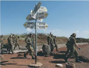  ?? (Baz Ratner/Reuters) ?? IDF SOLDIERS walk by signs at an observatio­n point on Mount Bental in the Golan Heights, west of the demilitari­zed zone between Israel and Syria, yesterday.