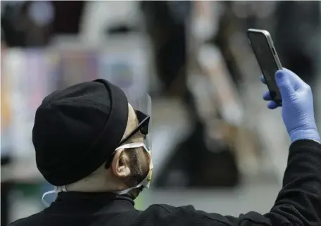  ?? AP FILE PHOTO ?? GETTING SMARTER: A man wears personal protective equipment while using his smartphone in Union Square, New York, on May 2. Google and Apple have teamed up on smartphone technology to automatica­lly notify people if they might have been exposed to the coronaviru­s.