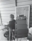  ??  ?? Jonas Holloway smiles next to a tower of packages mailed to his home in celebratio­n of his 5th birthday, after his mother's post of a handmade stuffed manta ray went viral on Reddit.