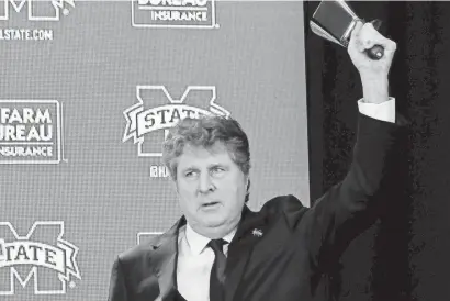  ?? ROGELIO V. SOLIS/AP ?? New Mississipp­i State football head coach Mike Leach rings in a new era at the school using a cowbell at a news conference last week in Starkville.