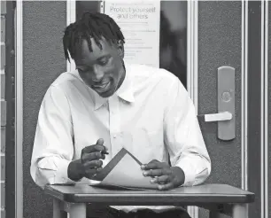  ?? MARK ZALESKI/SPECIAL FOR THE TENNESSEAN ?? Alex Okelo signs his letter of intent to play football at Michigan State during signing day on Wednesday in Nashville, Tenn.