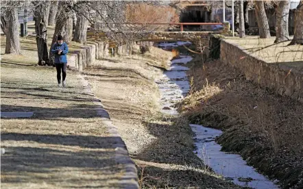  ?? LUIS SÁNCHEZ SATURNO/THE NEW MEXICAN ?? Julie Spencer of Santa Fe cools down Wednesday after a run along the Santa Fe River. The city plans to release roughly 200 acre-feet of water from Nichols Reservoir into the river this month, partly as an experiment to see whether the water can pass through an engineered canal at Cochiti Dam and flow all the way to Elephant Butte Reservoir.