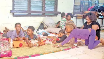  ??  ?? A Fijian family takes refuge in a temporary shelter from the strong damaging winds in the capital city of Suva.