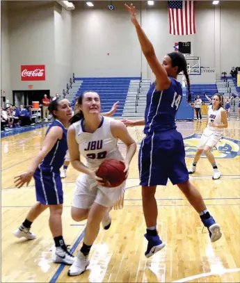  ?? Photo courtesy of JBU Sports Informatio­n ?? John Brown junior Jana Schammel drives by Oklahoma City’s Daniela Galindo during Thursday’s game at Bill George Arena. The Stars defeated the Golden Eagles 75-62.