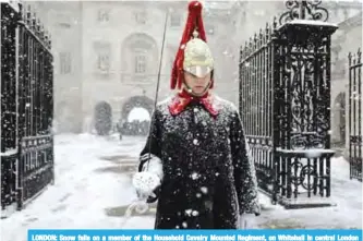  ?? —AFP ?? LONDON: Snow falls on a member of the Household Cavalry Mounted Regiment, on Whitehall in central London yesterday. Europe yesterday remained gripped by a blast of Siberian weather which has killed at least 24 people and carpeted palm-lined...