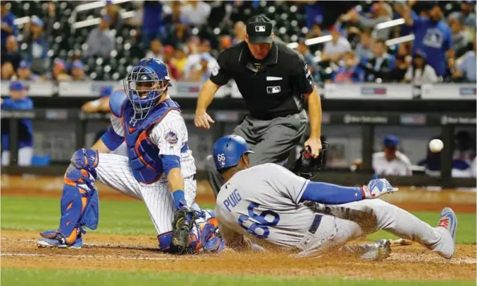  ??  ?? NEW YORK: Yasiel Puig #66 of the Los Angeles Dodgers slides safely home for a run in the ninth inning as Travis d’Arnaud #18 of the New York Mets can’t come up with the ball at Citi Field on Sunday in the Flushing neighborho­od of the Queens borough of...