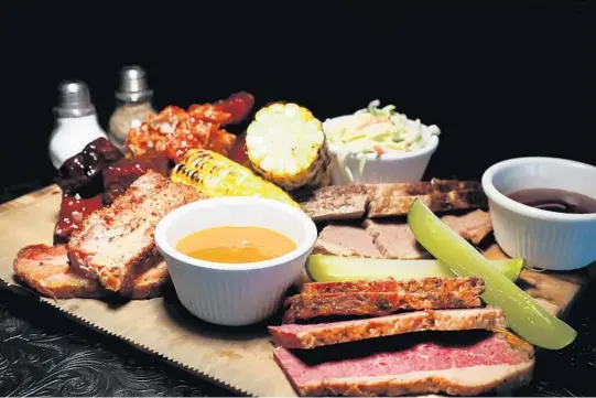  ?? CARLINE JEAN/SUN SENTINEL PHOTOS ?? The Kraft Feast, an assortment of smoked meat served with corn, fries and coleslaw at the Kraft Bistro & Deli in Fort Lauderdale.