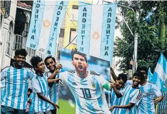  ?? DIBYANGSHU SARKAR / AFP ?? Un grupo de jóvenes sostiene un póster de Messi en Calcuta (India)