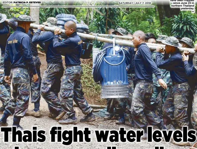  ??  ?? Soldiers carry a pump to help drain the rising flood water in a cave where 12 boys and their soccer coach have been trapped since June 23 in northern Thailand yesterday.