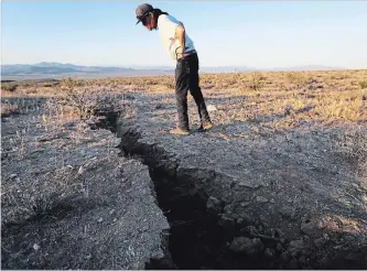  ?? MARIO TAMA GETTY IMAGES ?? A resident inspects a fissure after a 6.4-magnitude earthquake struck northeast of Los Angeles on Thursday.