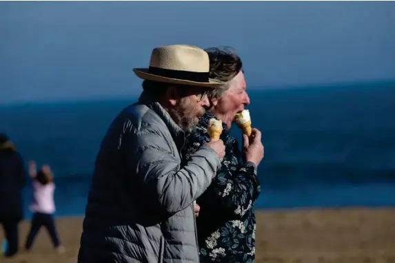  ?? (Reuters) ?? A couple eats ice cream on a beach in Tenby