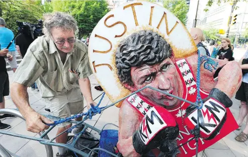  ?? NICK PROCAYLO/POSTMEDIA ?? George Rammell packs up his Trudeau model as Trans-Mountain pipeline protester Laurie Embree arrives to face the court on Tuesday. Embree was handed a seven-day jail term.