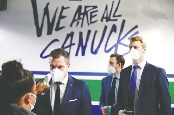  ?? — NHLI VIA GETTY IMAGES ?? Bo Horvat, from left, Brandon Sutter and Tyler Myers of the Vancouver Canucks get a temperatur­e check before their National Hockey League game against the Toronto Maple Leafs at Rogers Arena on Sunday. The Canucks had gone 24 days between NHL games.