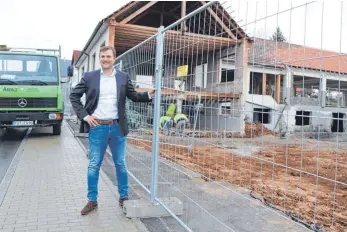  ?? FOTO: FRANK CZILWA ?? Gosheims Bürgermeis­ter André Kielack steht am Bauzaun des früheren Areals der Firma Xaver Weiss, wo jetzt Büroräume und sechs Wohneinhei­ten entstehen.