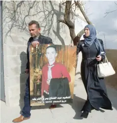  ?? — AFP ?? Rajaa and Yousri, the mother and father of Abdul Fatah al Sharif (portrait), head out into the streets in the West Bank town of Hebron on Wednesday, after watching on television the verdict of the trial of Israeli soldier Elor Azaria who killed their...