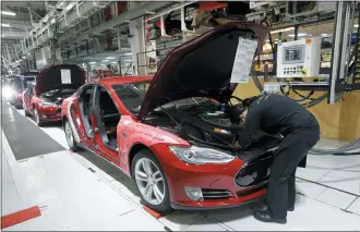  ?? JEFF CHIU — THE ASSOCIATED PRESS FILE ?? Tesla employees work on a Model S cars in the Tesla factory in Fremont, California. The parking lot was full at Tesla’s California electric car factory this week, an indication that the company was resuming production in defiance of an order from county health authoritie­s.