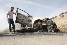  ?? AFP ?? A Palestinia­n man inspects a car, reportedly burnt by Israeli settlers on Friday, in the village of Al-Mughayer, east of the occupied West Bank city of Ramallah.