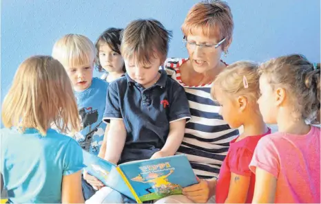  ?? FOTO: BERND WÜSTNECK, DPA ?? Vorlesen und gemeinsam Bücher anschauen ist ein Teil der Sprachförd­erung im Kindergart­en.