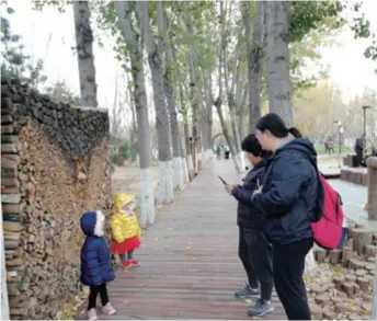  ??  ?? Visitors take photos at the Huilonggua­n Sport and Cultural Park on November 15