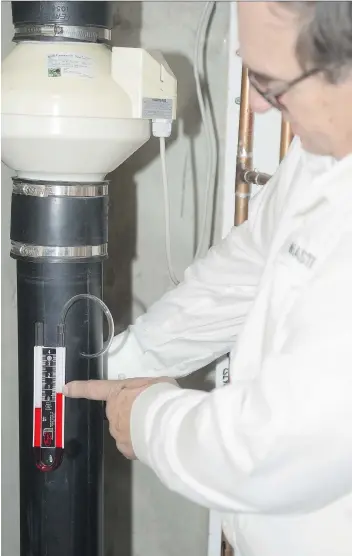  ?? MICHAEL BELL ?? Certified radon mitigation expert Frank Kirkpatric­k points to a manometer, part of a sub-slab depressuri­zation system installed in the basement of his Moose Jaw home. The system is said to be the most effective and reliable radon reduction technique to...