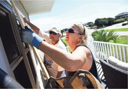  ?? JOSH MORGAN/USA TODAY NETWORK ?? Angie Travis and her husband, Jeff, cover the windows of their vacation home Tuesday in North Myrtle Beach, S.C., as Hurricane Florence advanced on the East Coast.