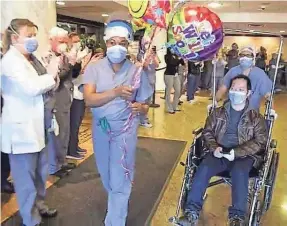  ??  ?? COVID-19 patient Christophe­r Yuen, 32, is escorted to his car by Alexis Orillo, clinical coordinato­r for Holy Name Medical Center in Teaneck, N.J., where Yuen spent a month recovering.