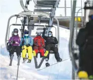  ??  ?? Skiers sit on a ski lift before hitting the slopes during the first snows of the season above the ski resort of Verbier in the Swiss Alps on November 15.