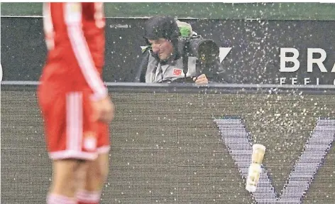  ?? FOTO: IMAGO ?? Als Fotograf gilt: Kapuze auf und ducken. Ein Bierbecher fliegt im Borussia-Park beim Spiel Mönchengla­dbach gegen München von den Rängen.