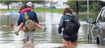  ?? GERALD HERBERT, AP ?? Don Noel carries daughter Alexis, 8, with his wife Lauren, on a flooded roadway in New Orleans.