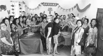  ??  ?? Cranfield (donning headgear at centre of left table) tosses ‘Yee Sang’ with members and guests.