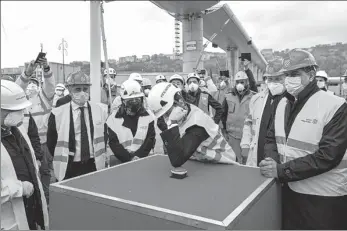  ?? FABIO FERRAR / LAPRESSE VIA ASSOCIATED PRESS ?? Italian Prime Minister Giuseppe Conte pushes a button with his elbow during a ceremony to mark the completion of a highway bridge, in Genoa, Italy, on Tuesday. The completion is hailed as a symbolic show of unity and hope amid the coronaviru­s emergency.