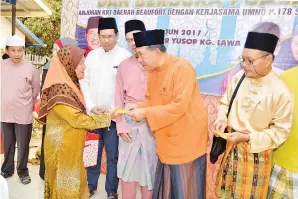  ??  ?? SAPAWI (dua kanan) menyampaik­an sumbangan kepada salah seorang warga emas.