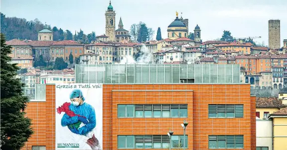  ??  ?? Il simbolo
La gigantogra­fia di solidariet­à con medici e infermieri esposta all’humanitas Gavazzeni di Bergamo, una delle aree più colpite dal virus in Italia