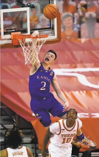  ?? Eric Gay / Associated Press ?? Kansas guard Christian Braun can’t complete the dunk as Texas guard Donovan Williams watches Tuesday in Austin, Texas. The Longhorns completed a rare sweep of the Jayhawks.