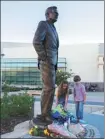  ?? AFP ?? Children place flowers at the base of the statue in tribute to former US President George H. W. Bush in College Station, Texas, on Saturday.