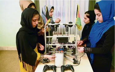  ?? — AFP ?? No small
feat: Teenage girls from the Afghanista­n Robotic House, a private training institute, working on a robot at the Better Idea Organisati­on centre in Herat.