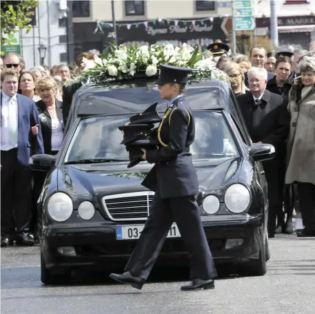  ??  ?? A Garda carries the caps of the pallbearer­s of the coffin of their colleague, Det. Garda Colm Horkan before it is carried to St James’ Church in Charlestow­n on Sunday.