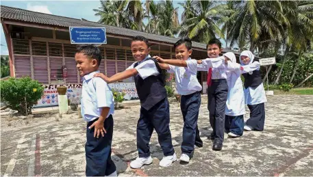  ??  ?? Mohamad Hairi (in front) went to school with his older brother Mohamad Harith (second right) and sister Saidatul Husna (second left) at SK Tebik Rebak on the first day. — Bernama