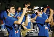  ??  ?? Wearing masks they only take down when playing their instrument­s, members of the brass section of the Walton High School marching band perform in the end zone.