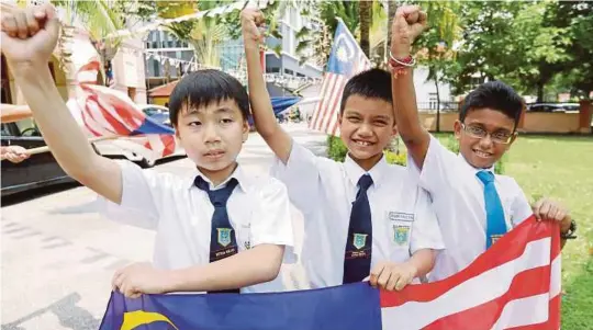  ?? [FOTO RAMDZAN MASIAM/BH] ?? Kah Ho, Amir Fauzan dan Sarinder teruja untuk menyambut Hari Kemerdekaa­n ketika ditemui selepas tamat sesi persekolah­an di luar SK Wellesley, di Georgetown, semalam.