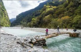  ?? ALEXANDRA REYNOLDS VIA AP ?? This photo shows trekkers crossing the glacier-fed Mo Chuu River on the hike from Gasa to the Laya Highlands for the second annual Royal Highlander festival. The festival is accessible only on foot, a 36-mile roundtrip up to nearly 13,000feet altitude.