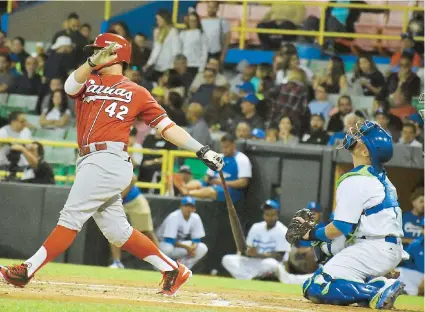  ??  ?? David Vidal, de los Criollos, conecta un jonrón por el bosque de la izquierda en la quinta entrada para darle en ese momento ventaja a si equipo 3-0. El receptor Christian Vázquez, de Santurce observa el batazo.