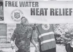  ?? AP Photo/ross D. Franklin ?? In this June 15, 2021 file photo, a pedestrian holds a bottle of cold water at a Salvation Army hydration station during a heat wave as temperatur­es hit 115-degrees in Phoenix. The Southwest US continued to bake on Saturday, June 19, and weather forecaster­s kept warnings in effect for excessive heat in Arizona, nevada and desert areas, at least through the weekend.