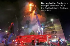  ??  ?? Blazing battle: Firefighte­rs trying to douse the fire at the Enel building in Santiago. — Reuters