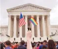  ?? JACQUELYN MARTIN/ASSOCIATED PRESS ?? A man holds a U.S. flag and a rainbow flag outside the Supreme Court in June of 2015 after the court legalized gay marriage. Some legal experts feel that ruling could be challenged.